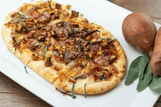 A long pizza topped with autumnal ingredients