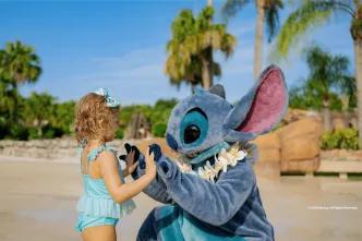 An adorable character meet-and-greet at a sunny Walt Disney World location, showing a young child playing with Stitch on the beach, a great example of fun outside the main theme parks for young families.