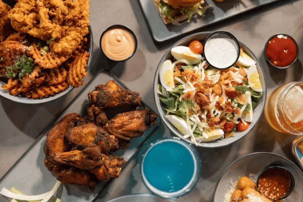 Food at Crush Yard Pickleball Club & Restaurant Many dishes available with chicken wings, fries and an egg salad with different sauces including ketchup, pink sauce and more.