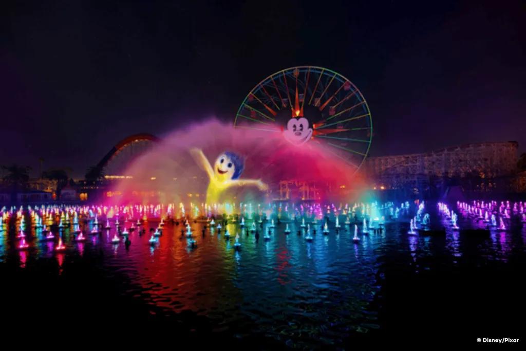World of Color Joy from Inside Out projected onto a water fountain with a Mickey Mouse ferris wheel in the background