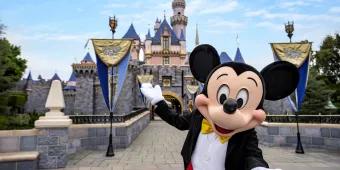 Mickey Mouse standing in front of Sleeping Beauty Castle at Disneyland Resort