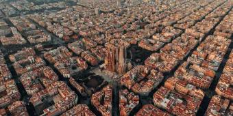 Layout of Barcelona with a view of the Sagrada Familia cathedral. The city is laid out with straight roads and buildings shaped in squares. They all have the same colour scheme with white and orange walls and roofs.