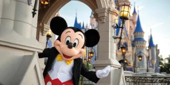 Mickey Mouse standing in front of Cinderella Castle with his arm outstretched