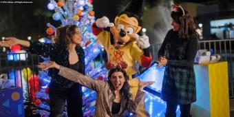 Three women posing for a selfie with Max from A Goofy Movie dressed as Powerline in front of a Christmas tree