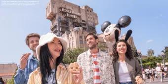 A group of four friends in their twenties walking in front of Tower of Terror in Walt Disney Studios