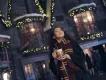 Christmas in Orlando A young woman wearing a scarf and wizard robes drinking Butterbeer in front of decorated buildings