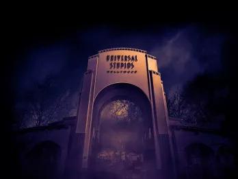 A large archway reading Universal Studios Hollywood surrounded by fog at night