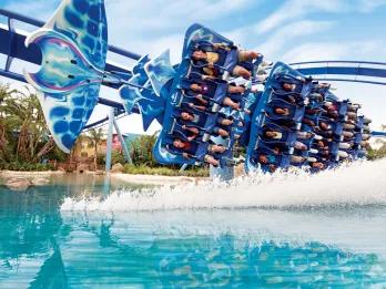 Ride shaped like manta ray in motion, curving round bend on top of lake with water being sprayed up towards the riders