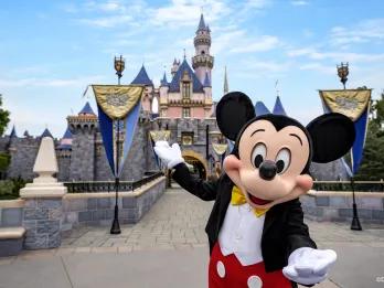 Mickey Mouse standing in front of Sleeping Beauty Castle at Disneyland Resort