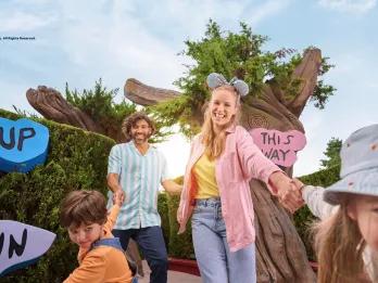 A mum and dad being dragged towards the camera by their son and daughter in the middle of a hedge maze