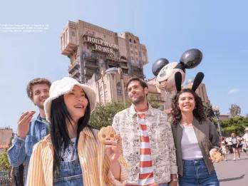 A group of four friends in their twenties walking in front of Tower of Terror in Walt Disney Studios