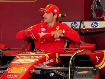 Famous Ferrari driver hopping in his famous Formula 1 Ferrari car in the garage with red walls. He is wearing a red cap which is branded and is wearing a red hoodie with the Ferrari logo on it.