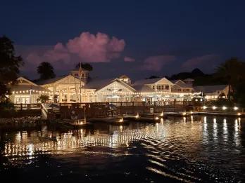 Beautiful white building lit up at night with yellow lighting. It is overlooking a huge lake.