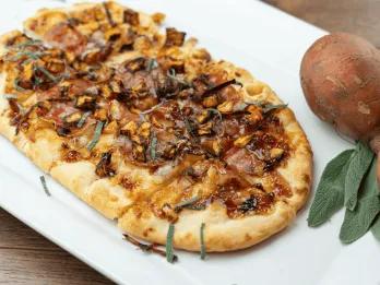 A long pizza topped with autumnal ingredients