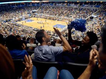 Two friends high-fiving while watching an Orlando Magic game