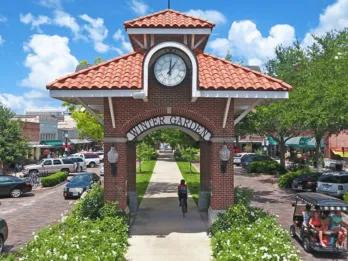 Winter garden sign on an arch with roads either side and people driving golf carts and cars. 