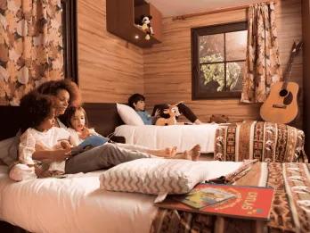 A family relaxing and reading on beds in a wooden cabin at Davy Crockett Ranch