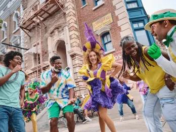 People dancing with Mardi Gras performers dressed in bright coloured, feathered costumes