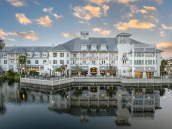 A beautiful white large hotel on the edge of a large lake, reflecting in the water and the gorgeous clear sky above. 