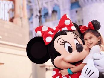 A young girl hugging Minnie Mouse in front of Cinderella Castle at Walt Disney World