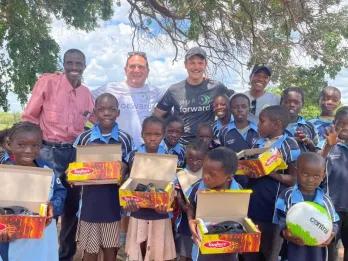 Play It Forward Lots of children holding boxes of donated shoes, sports kits and school uniform.